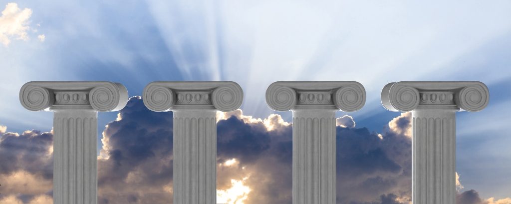 Image of 4 white pillars reaching up, with light shining through clouds in the background. 